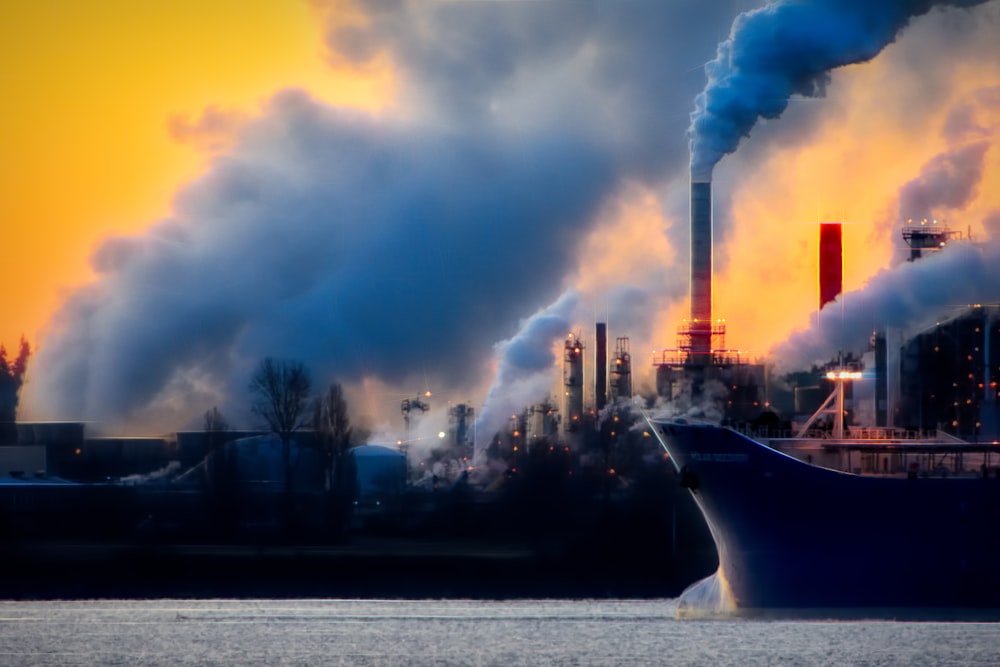 a large boat in a body of water near a factory