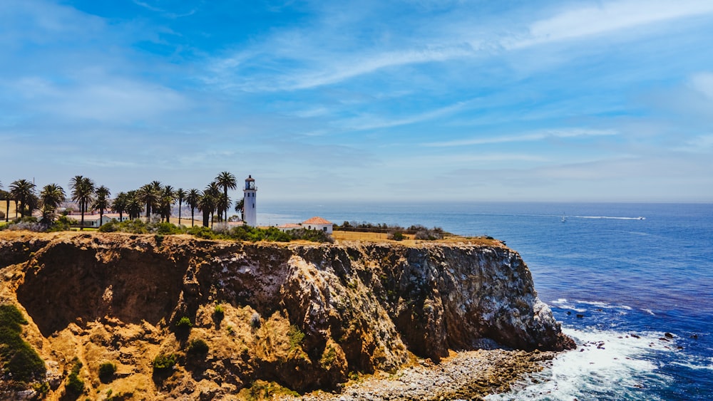 white concrete building on cliff near body of water during daytime