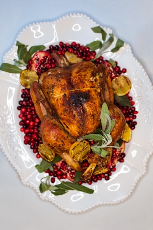 Close-up of a golden turmeric-glazed turkey alternative surrounded by fresh herbs.