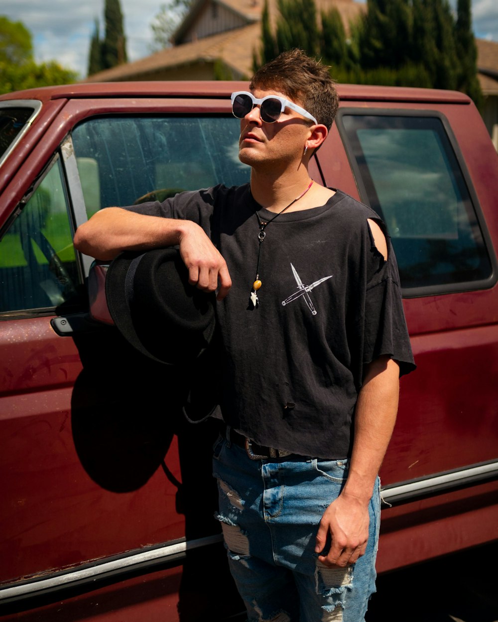 man in black nike crew neck t-shirt and blue denim jeans standing beside red car