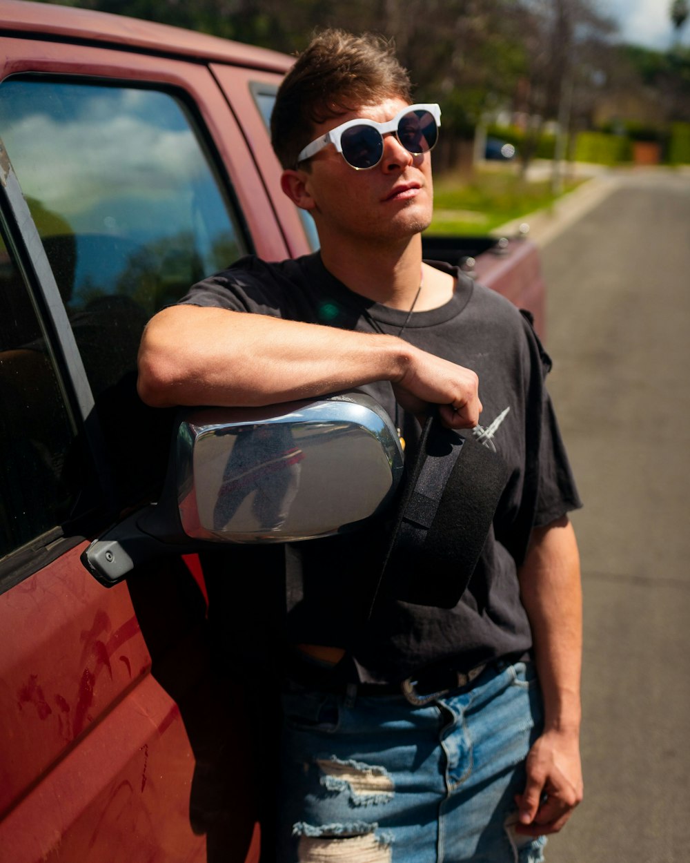 man in black crew neck t-shirt and blue denim jeans wearing black sunglasses