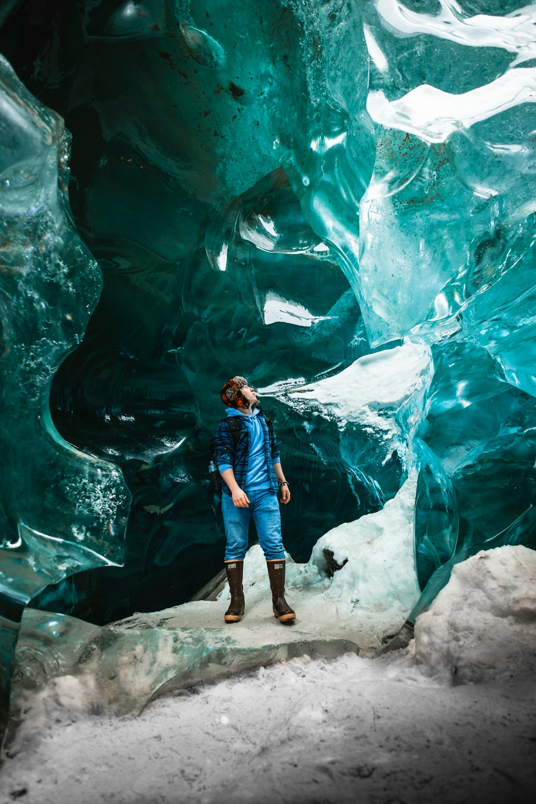 man in blue and white plaid dress shirt and blue denim jeans standing on rock