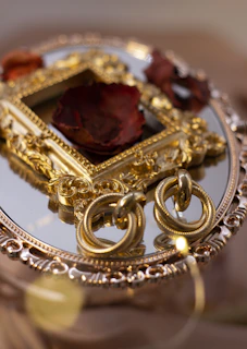 Elegant pair of gold hoop earrings displayed on a light wooden tray with a hint of greenery