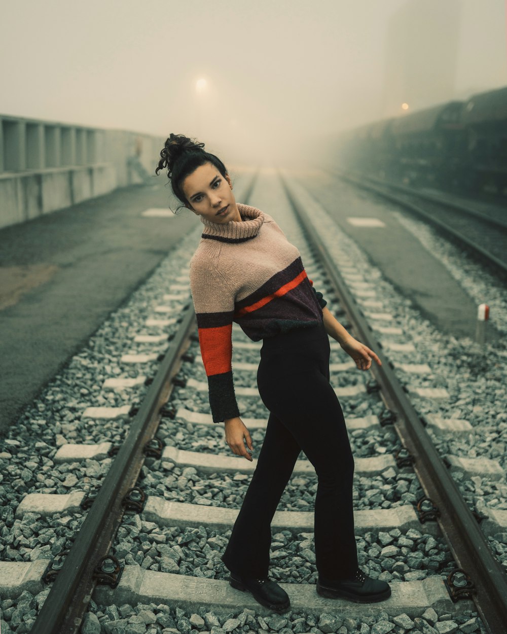 woman in black pants standing on train rail during daytime