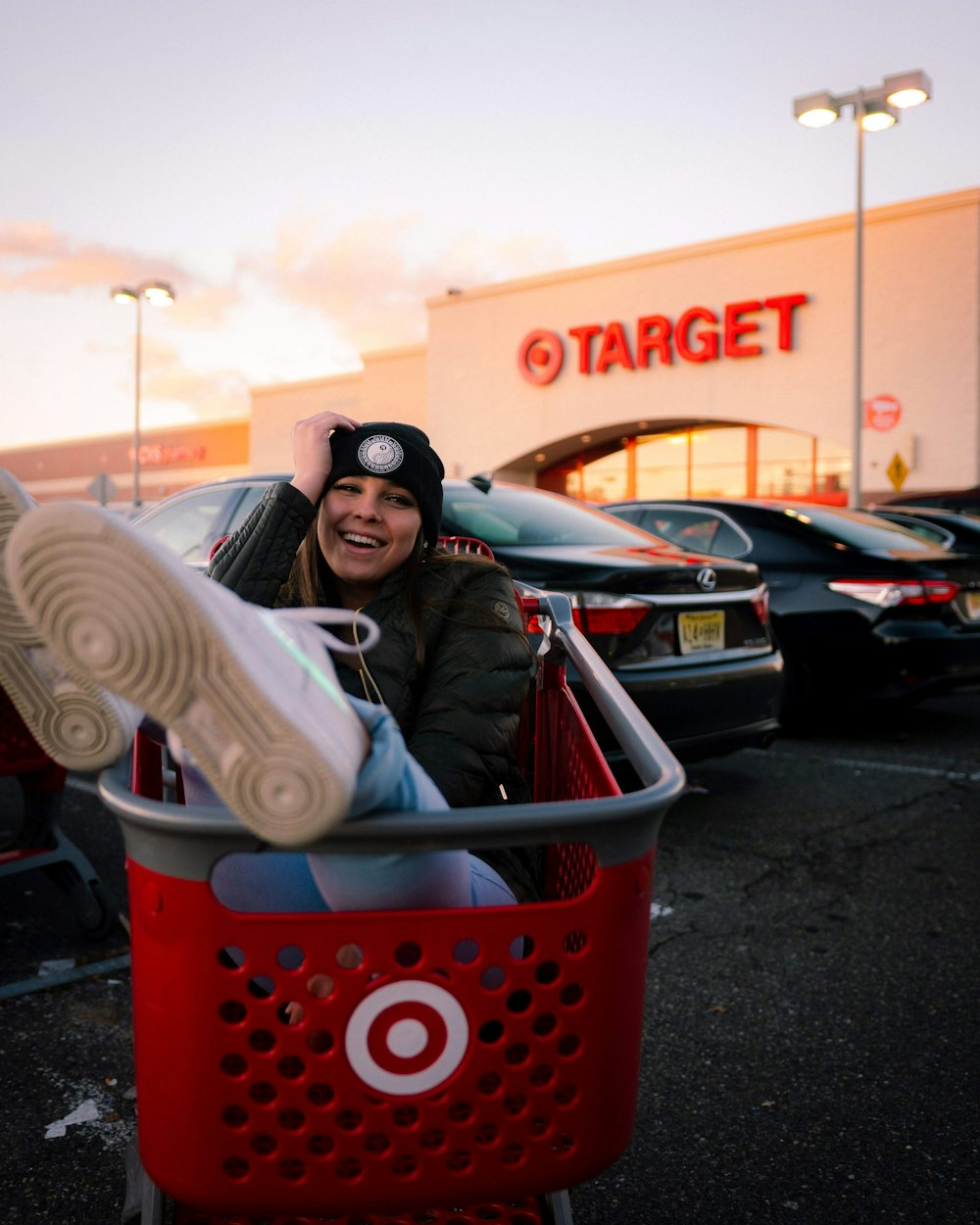 woman in blue jacket sitting on red plastic laundry basket