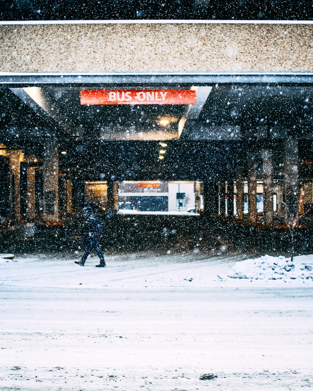 person walking on snow covered road near brown building during daytime