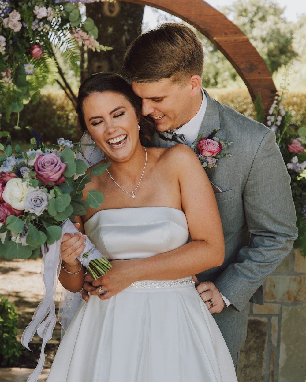 man in gray suit jacket hugging woman in white tube dress