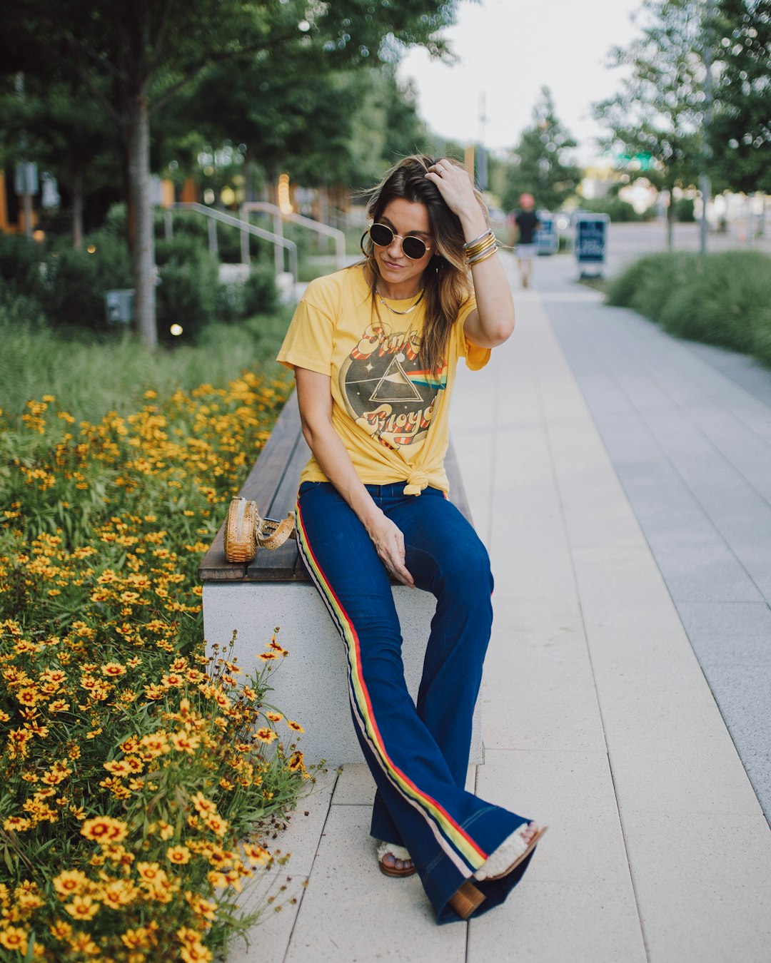 woman in yellow t-shirt and blue pants sitting on concrete pathway during daytime