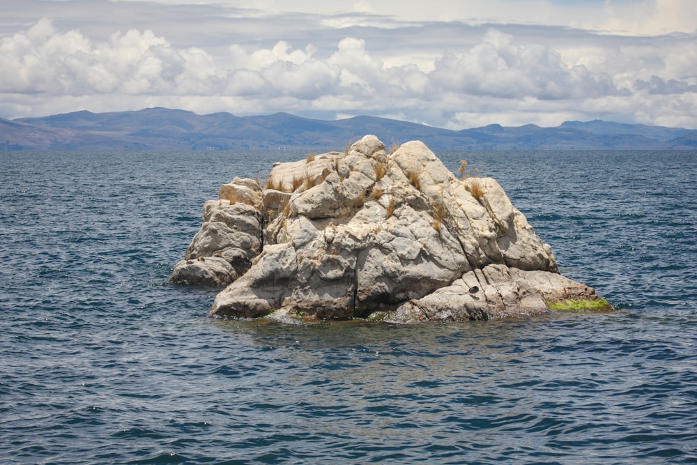 brown rock formation on sea under white clouds and blue sky during daytime