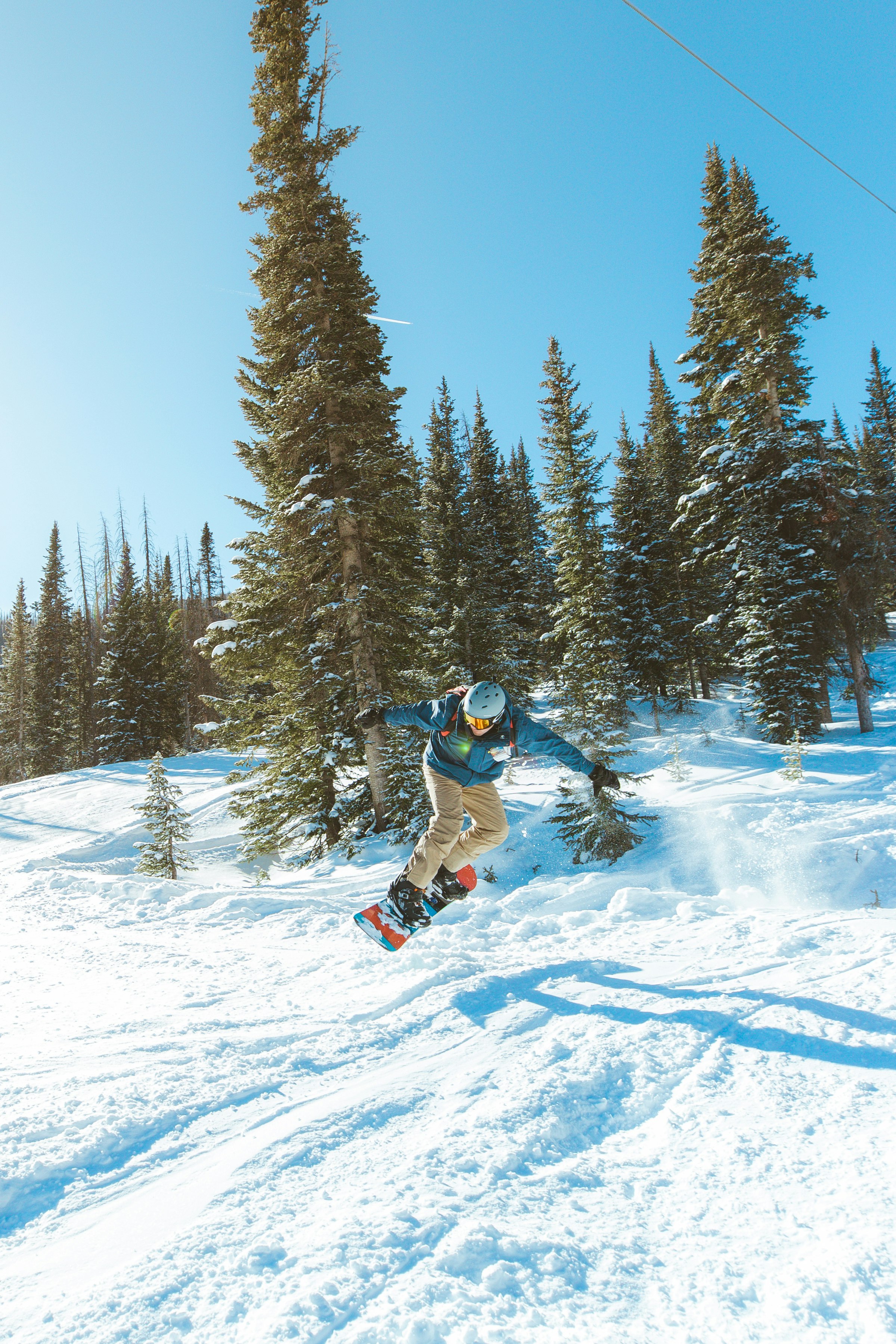 man in blue jacket and red pants riding on snowboard during daytime