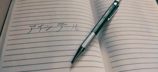 Close-up of handwritten Japanese characters on a notebook with colorful pens.