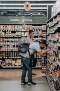man in gray polo shirt and blue denim jeans standing on grocery store
