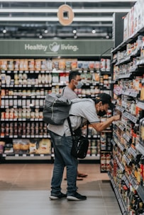 man in gray polo shirt and blue denim jeans standing on grocery store