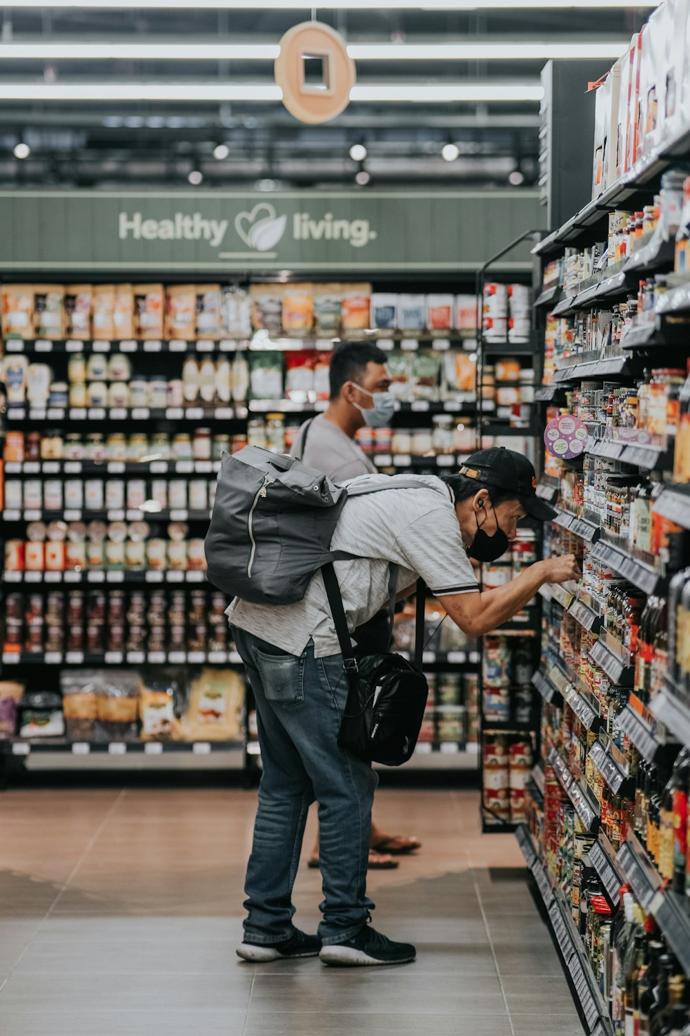 man in gray polo shirt and blue denim jeans standing on grocery store