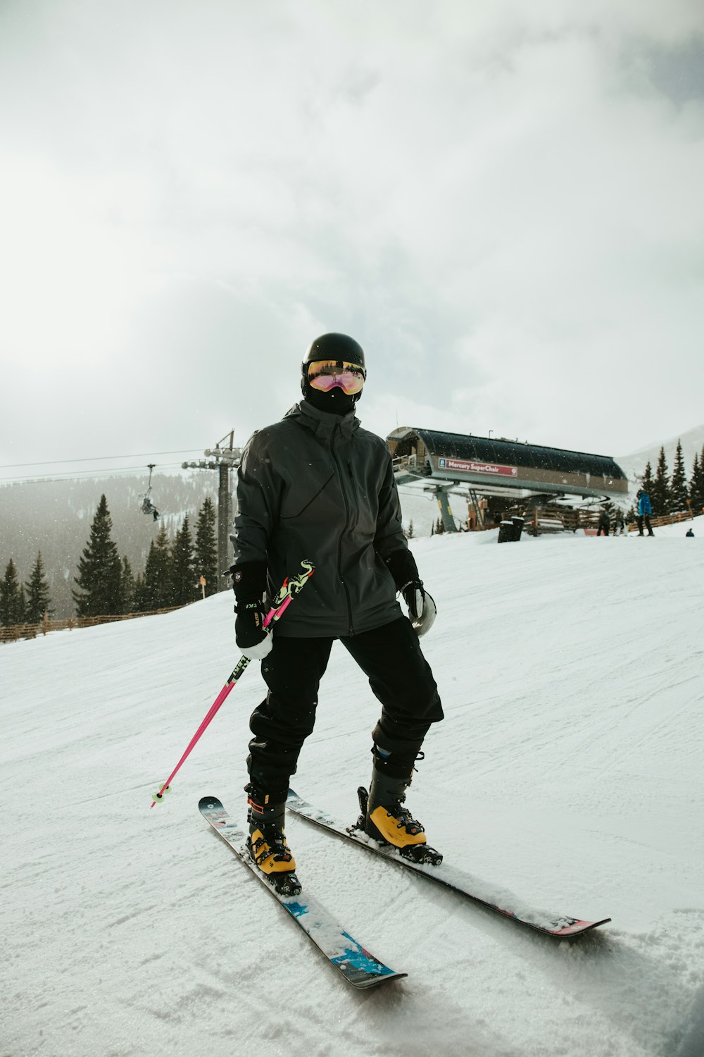 Man met zwarte ski outfit op ski's boven aan de besneeuwde berg