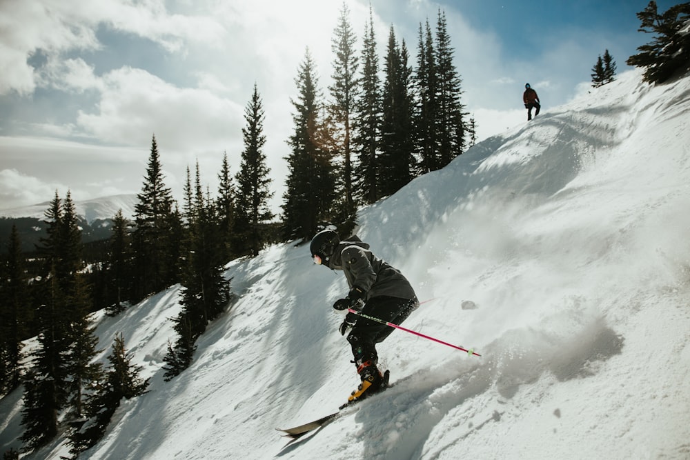 man in black jacket and blue pants riding ski blades on snow covered mountain during daytime