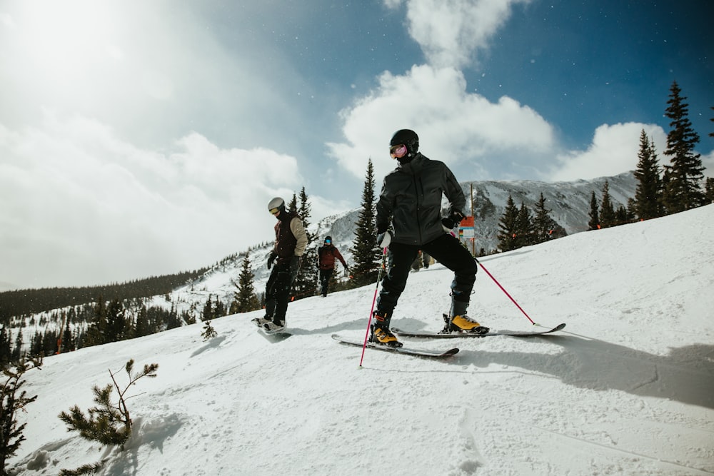 man in black jacket and blue pants riding on ski blades on snow covered mountain during