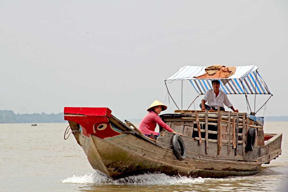 man and woman sitting on brown wooden boat on sea during daytime