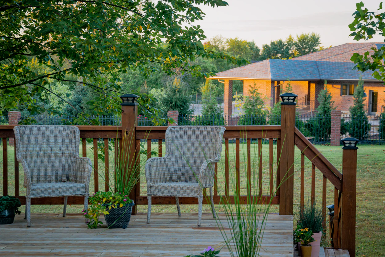 Wicker chairs on a wood deck with a railing