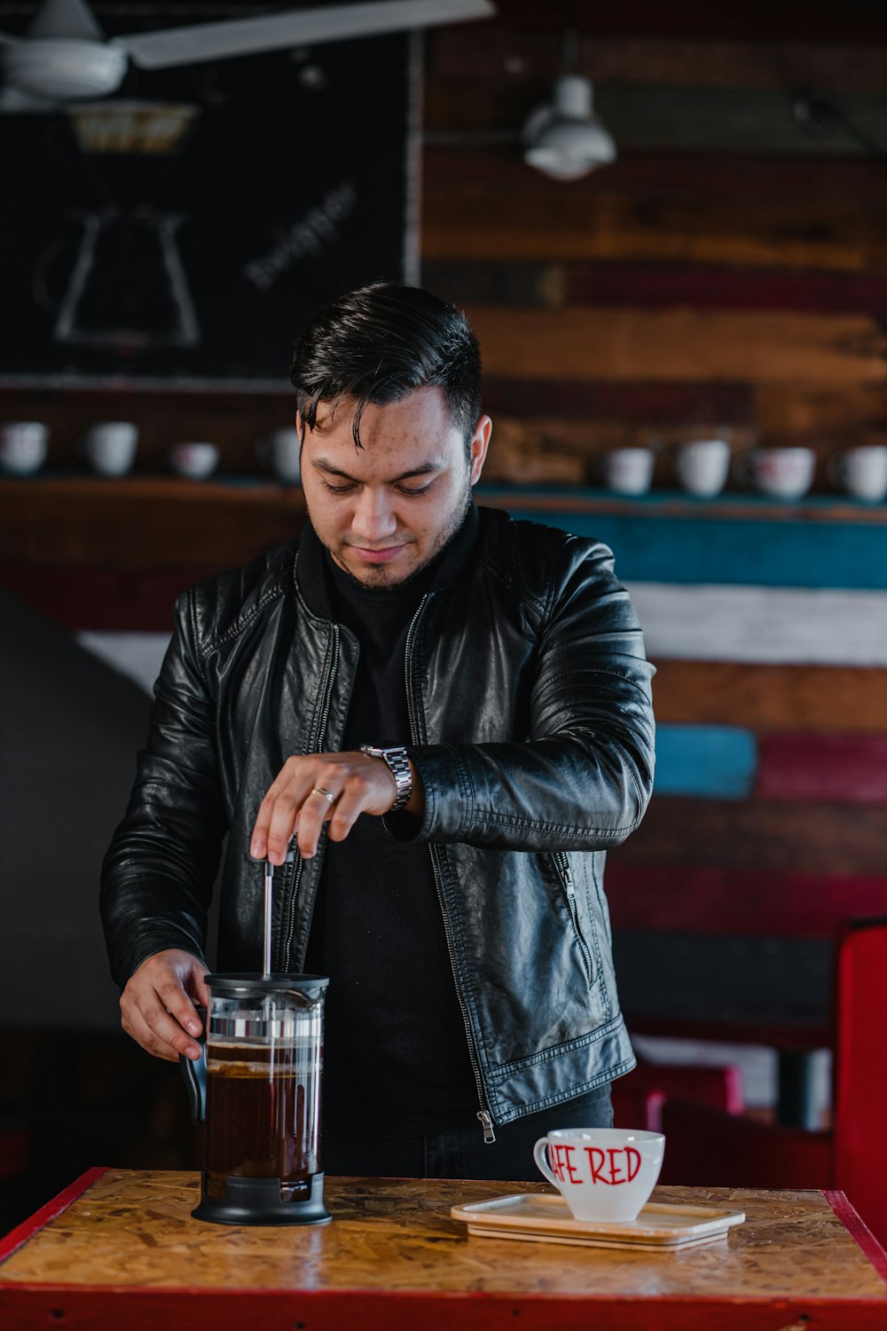 man in black leather jacket holding clear glass mug