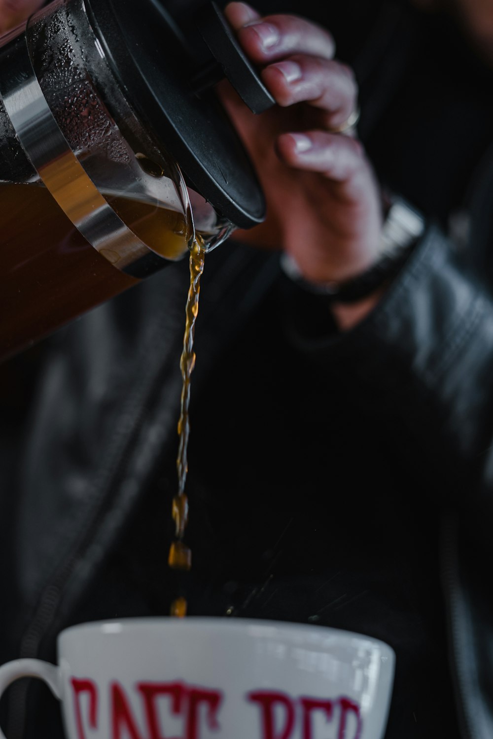 person holding brown and black tumbler