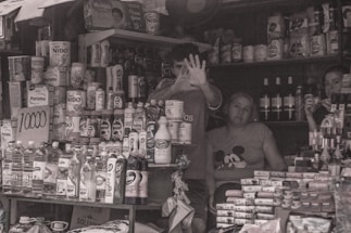 Image of a friendly store clerk assisting customers in a small grocery store.