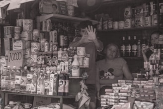 A young local shop owner arranging shelves in a village retail store.