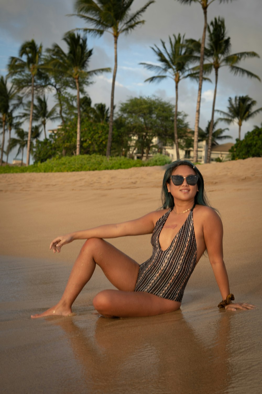 woman in black and white stripe swimsuit sitting on brown sand during daytime