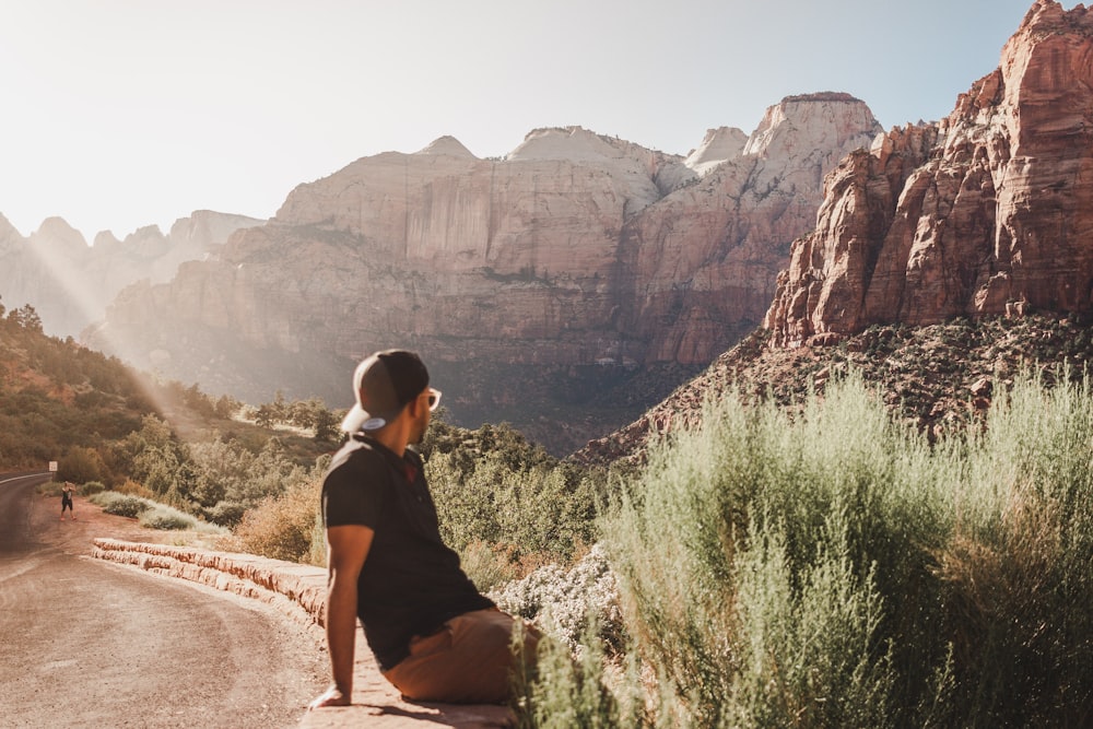 woman in black tank top sitting on rock formation during daytime