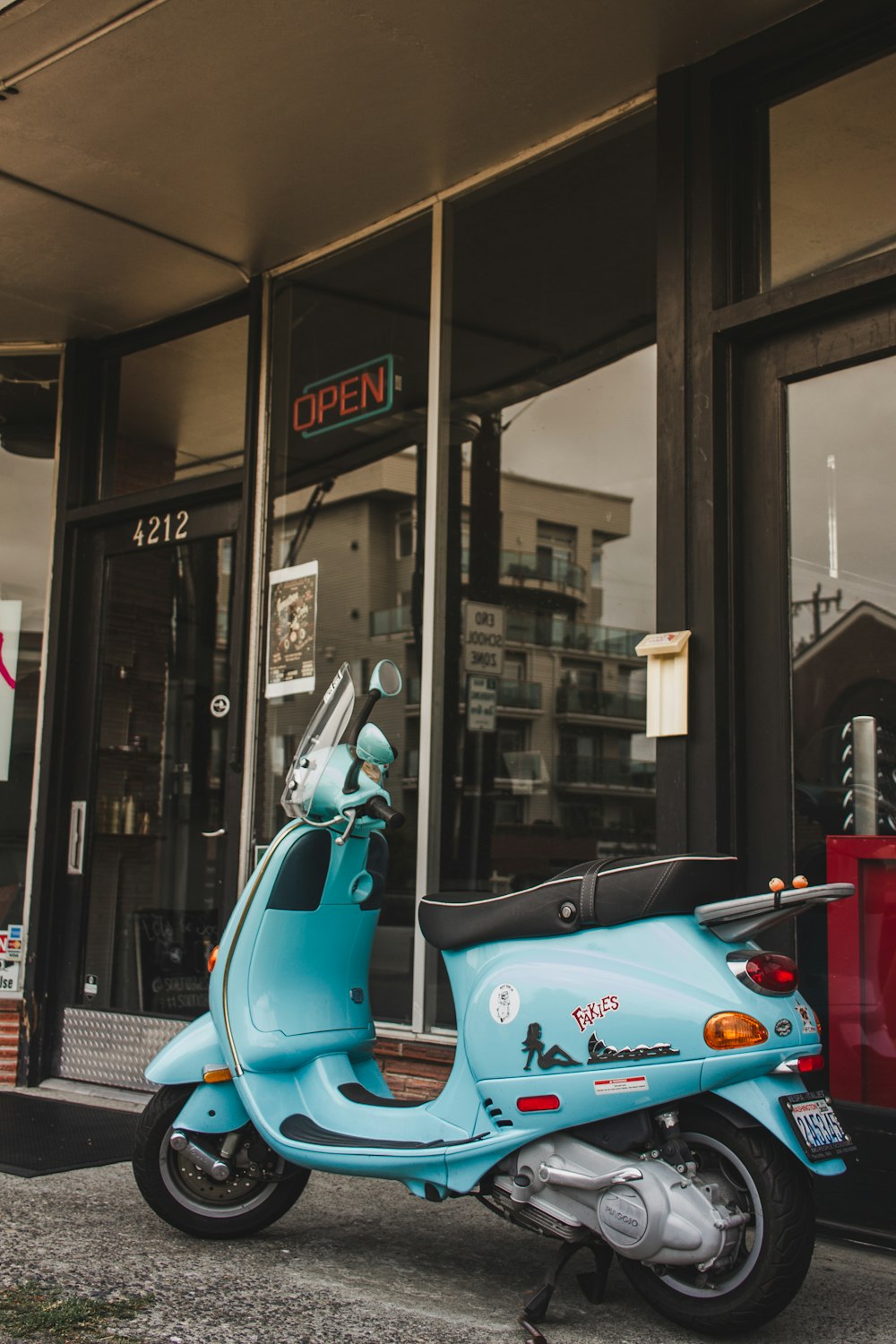 blue and white motor scooter parked beside store during nighttime