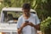 man in white crew neck t-shirt holding black smartphone