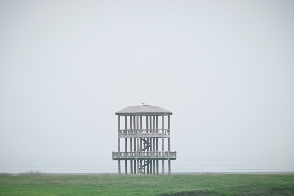 white wooden tower on green grass field under white sky during daytime