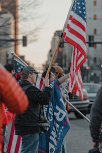 A group of diverse Americans standing united with flags and banners at a community rally.