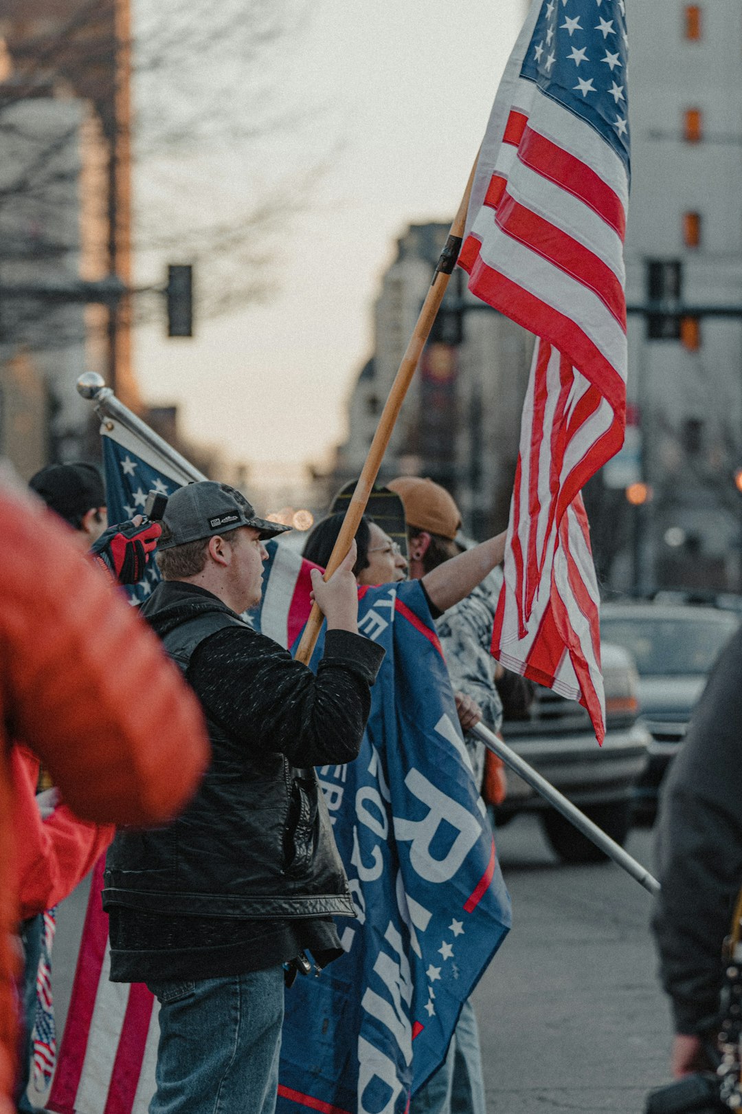 man in blue jacket holding flag of us a during daytime