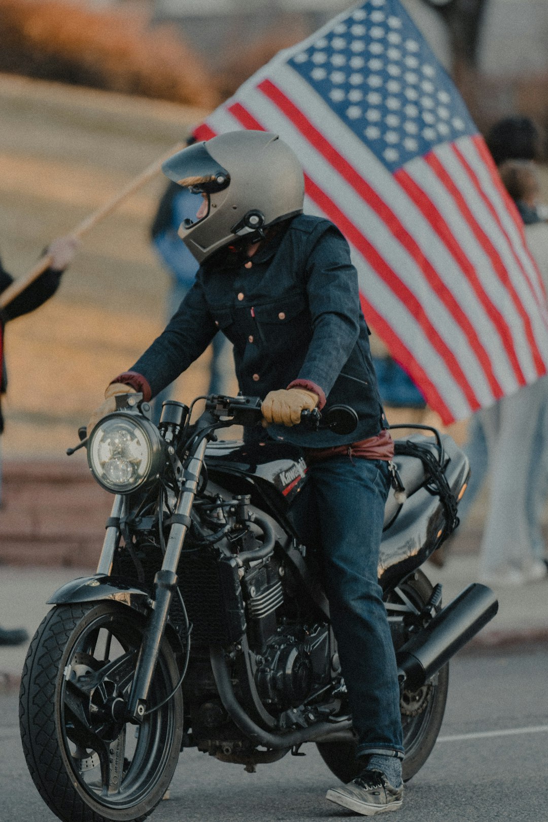 man in black jacket riding black motorcycle with us flag on his back