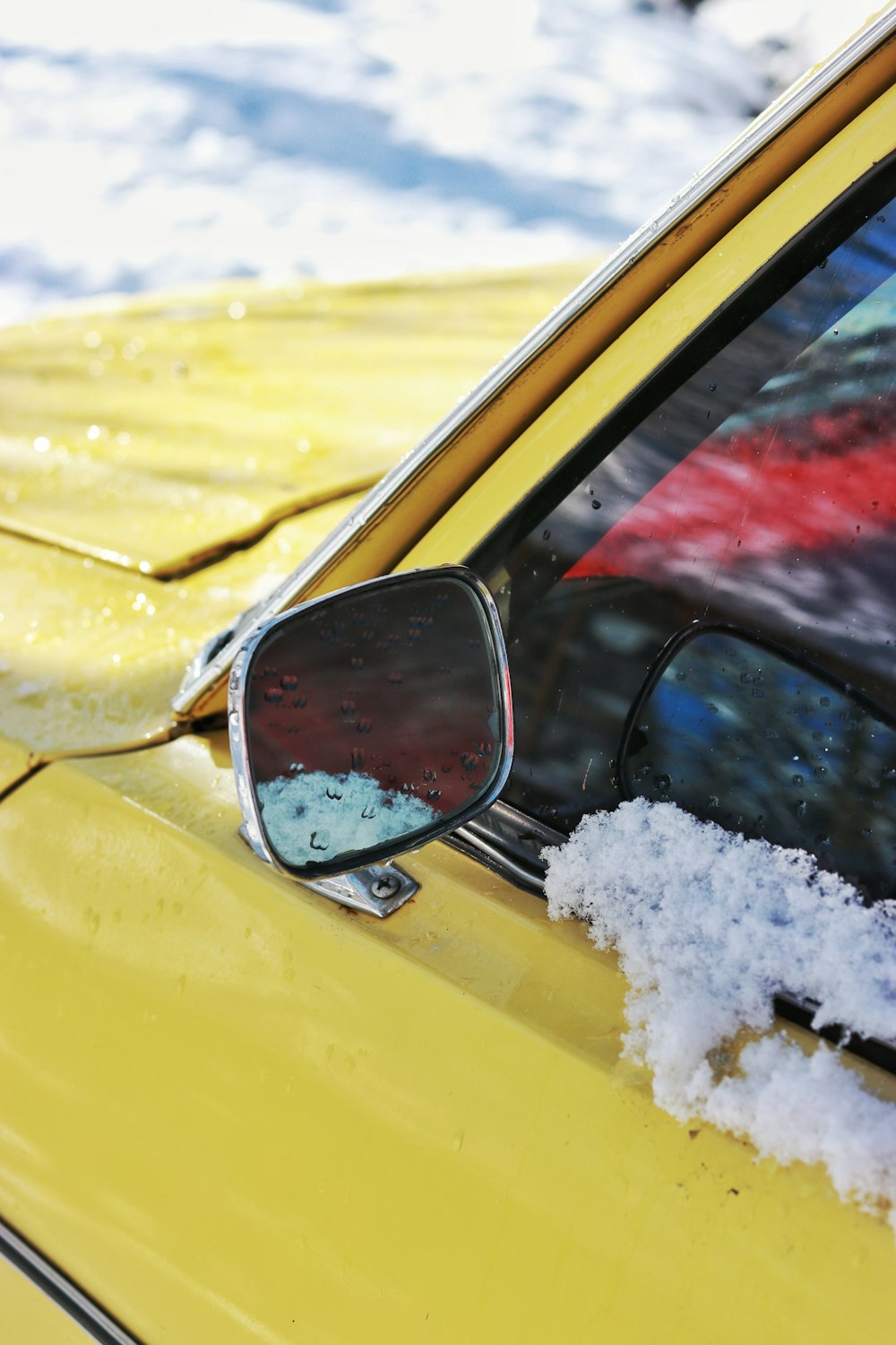 yellow car with snow on side mirror