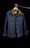 A denim jacket hangs on a wooden hanger against a dark background. The jacket features a brown collar, two front flap pockets with metal buttons, and detailed stitching. The lighting creates a focus on the texture of the fabric and the structure of the garment.