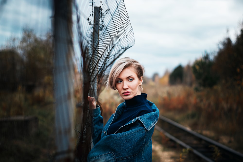 girl in blue denim jacket standing on train rail during daytime