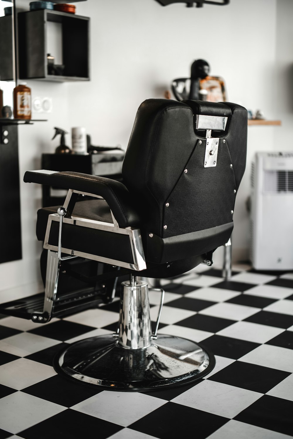 白い部屋の黒い革の理髪店の椅子