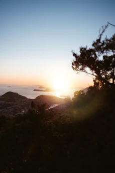 A serene coastal view of Kythera island at sunset, with gentle waves and lush greenery.