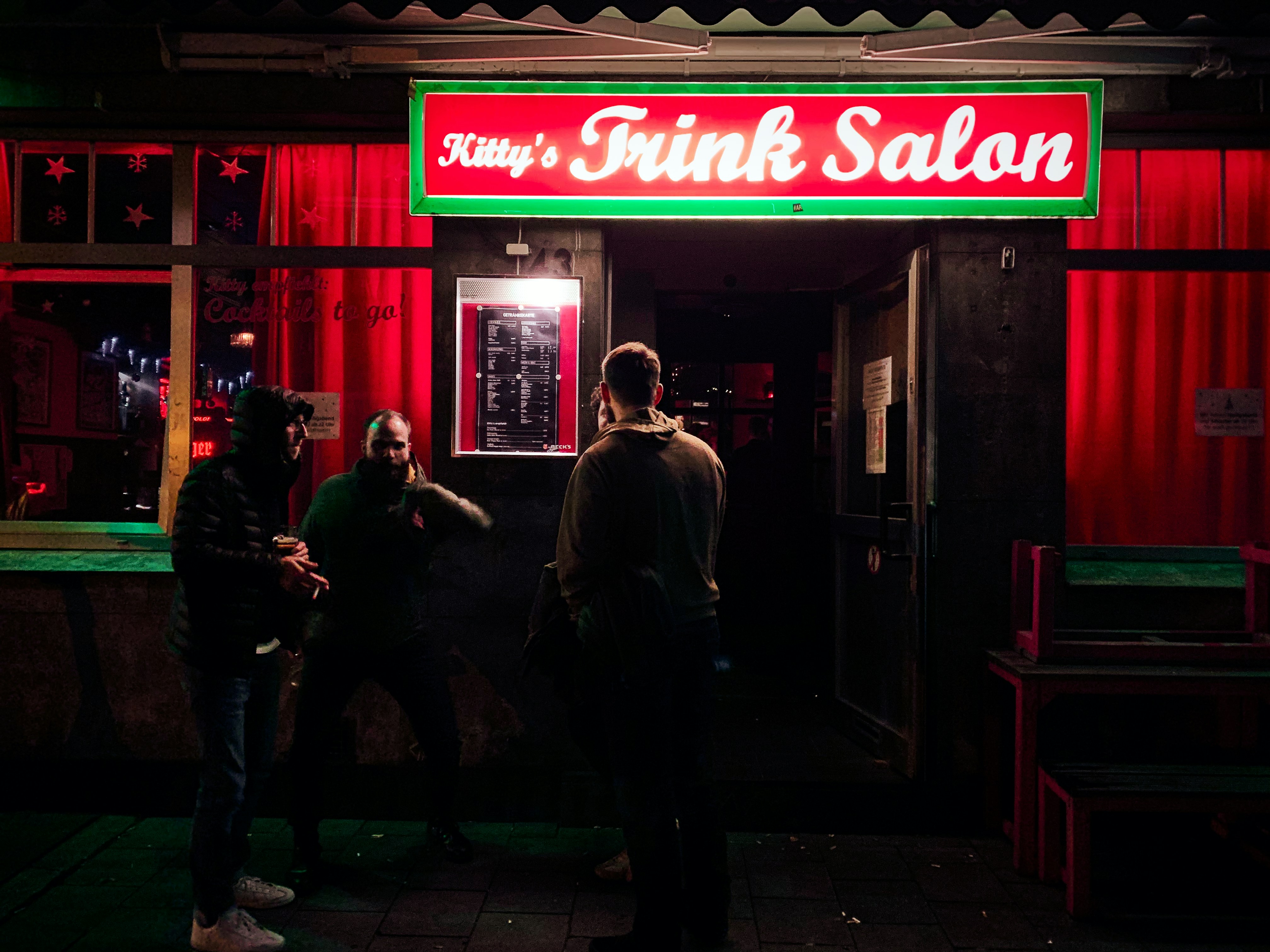 people walking on sidewalk near red and white store during daytime