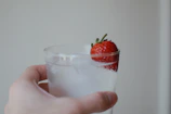Close-up of a hand holding a glass of water next to fresh fruits