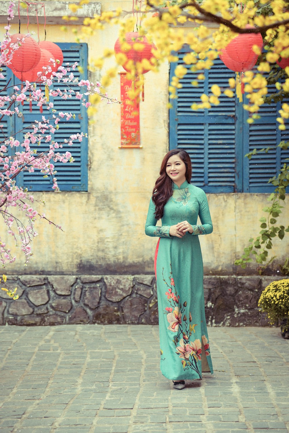 Femme en robe verte à manches longues debout près du mur bleu et blanc