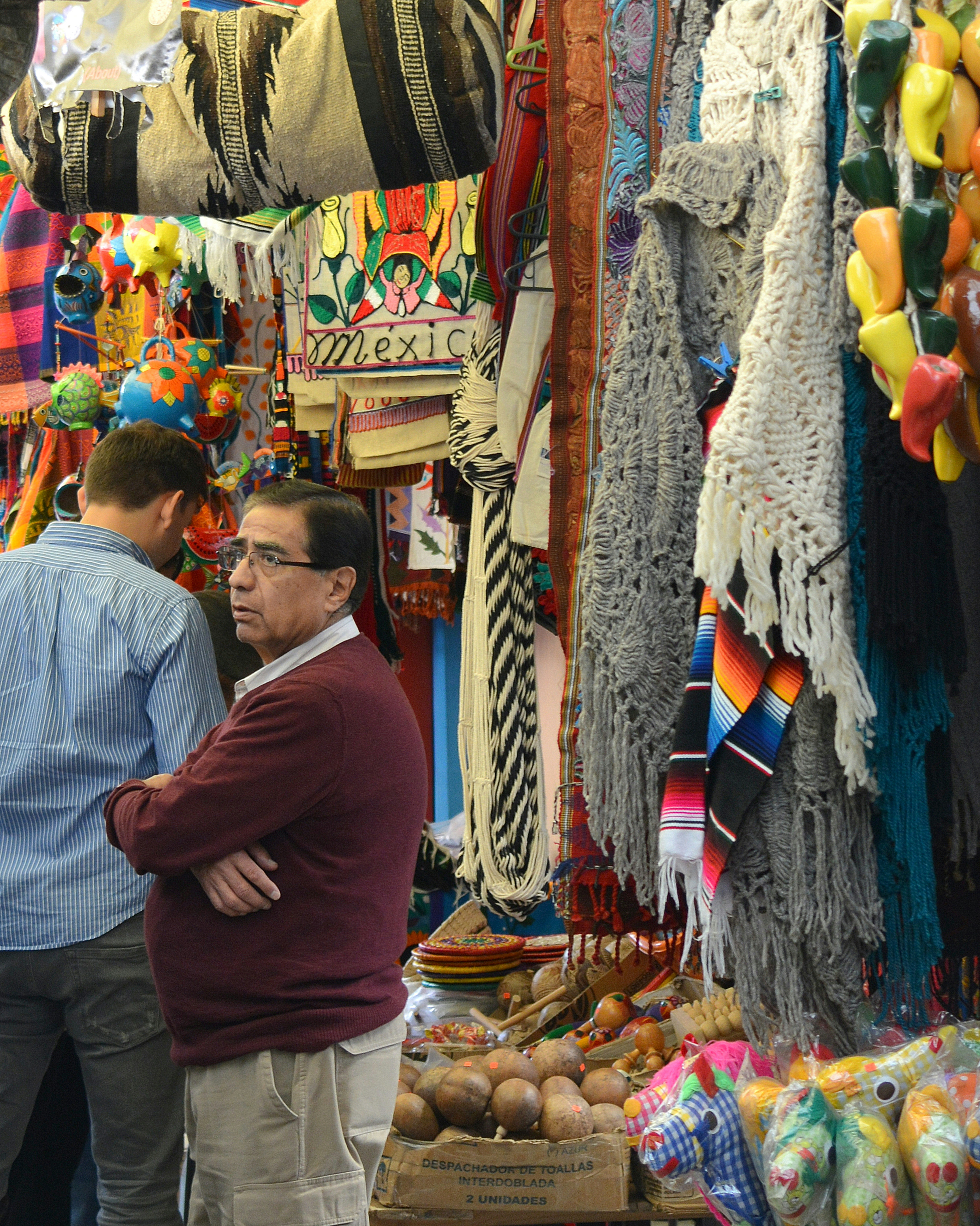 man in maroon sweater standing in front of assorted shoes