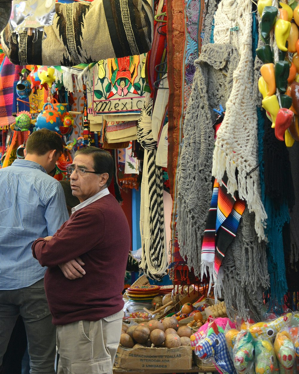 적갈색 스웨터를 입은 남자가 여러 신발 앞에 서 있다