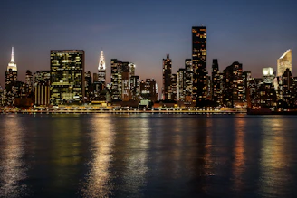 city skyline across body of water during night time
