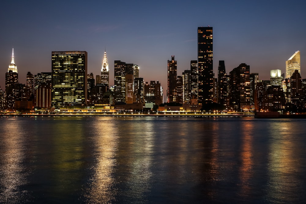 city skyline across body of water during night time