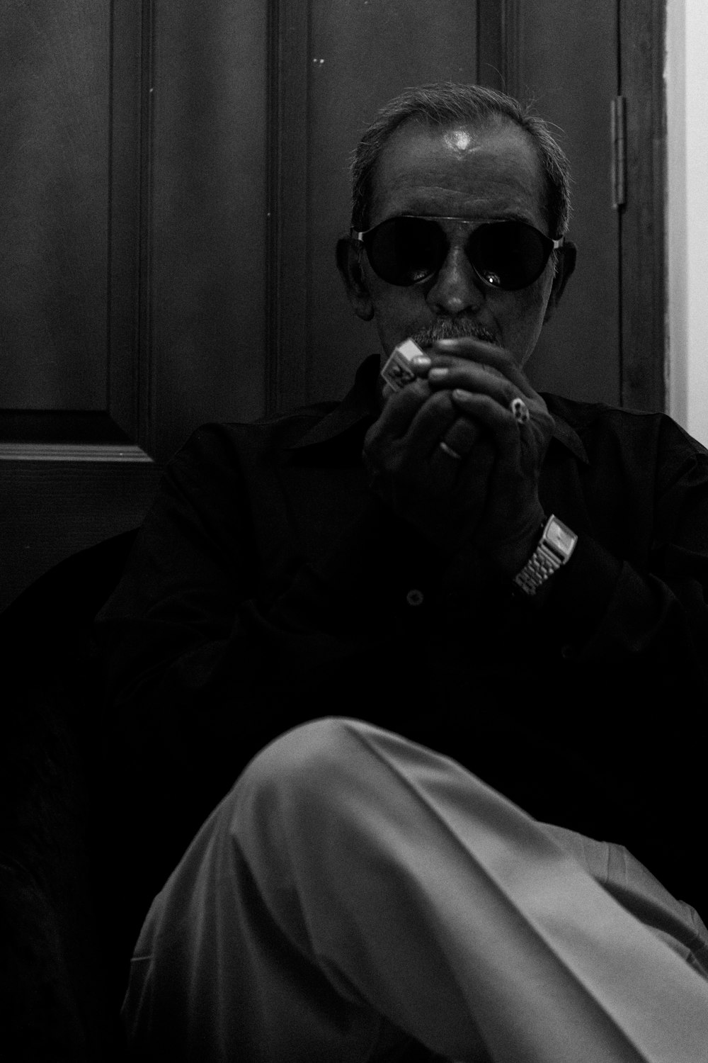 man in black coat and sunglasses sitting on chair