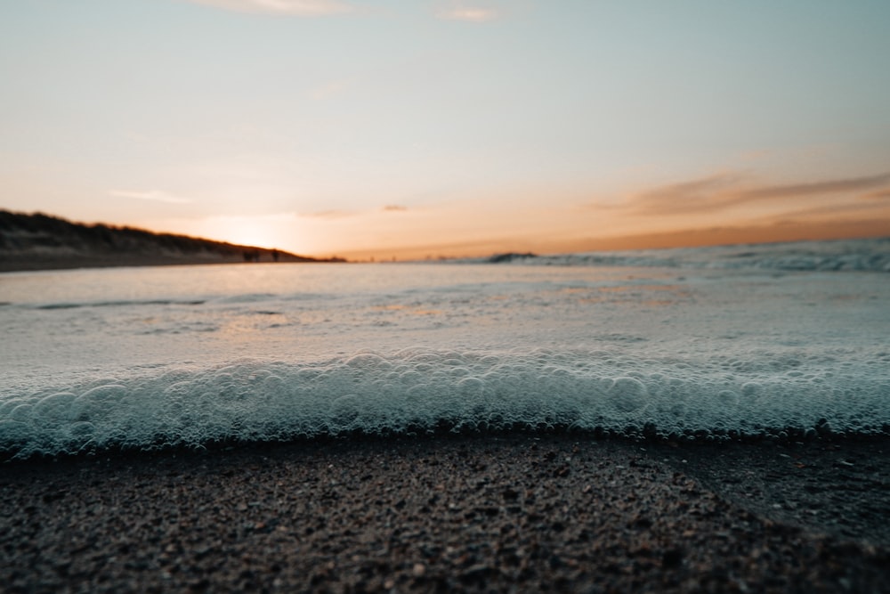 ocean waves crashing on shore during sunset