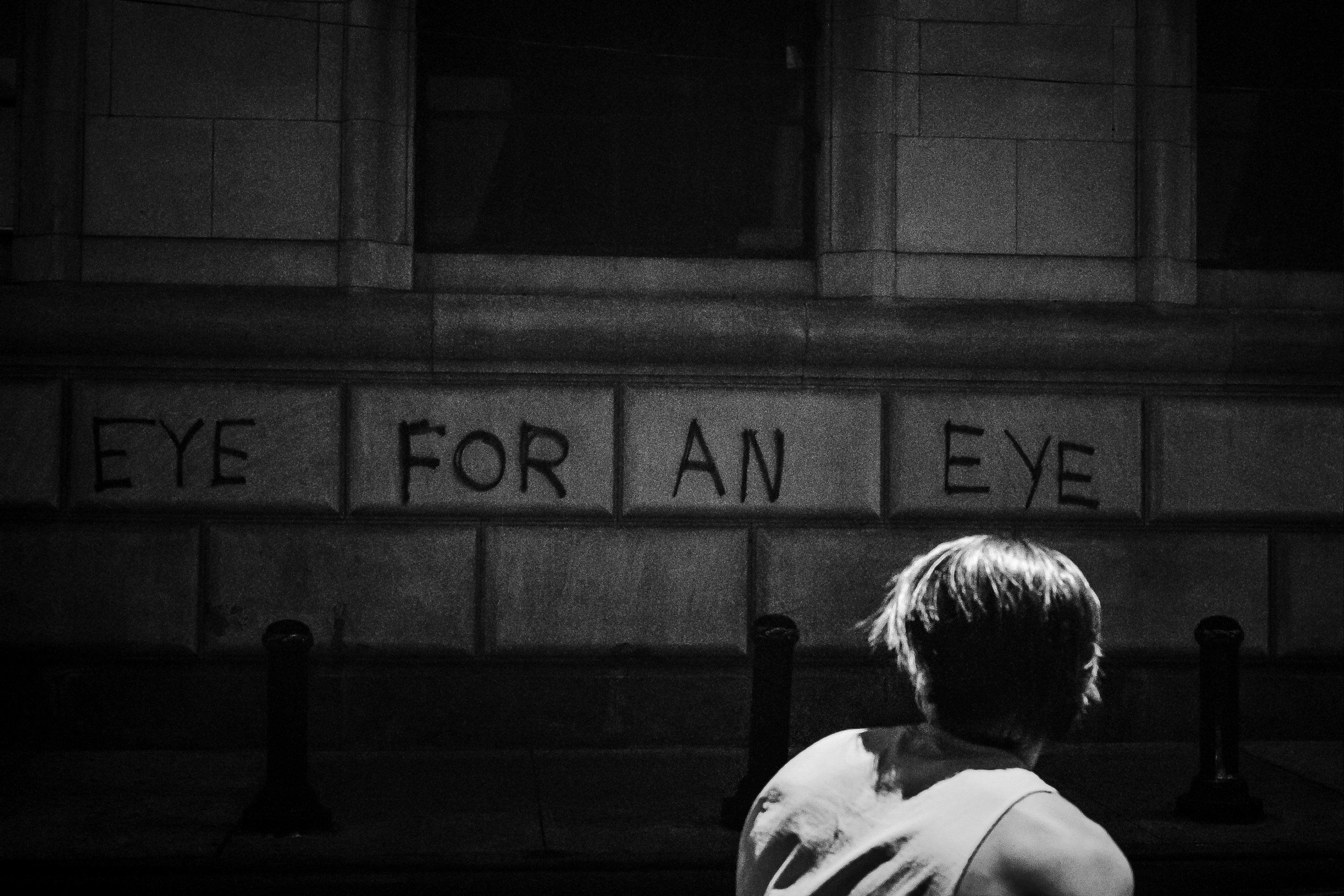 foto em tons de cinza do homem na camisa branca sentado no banco